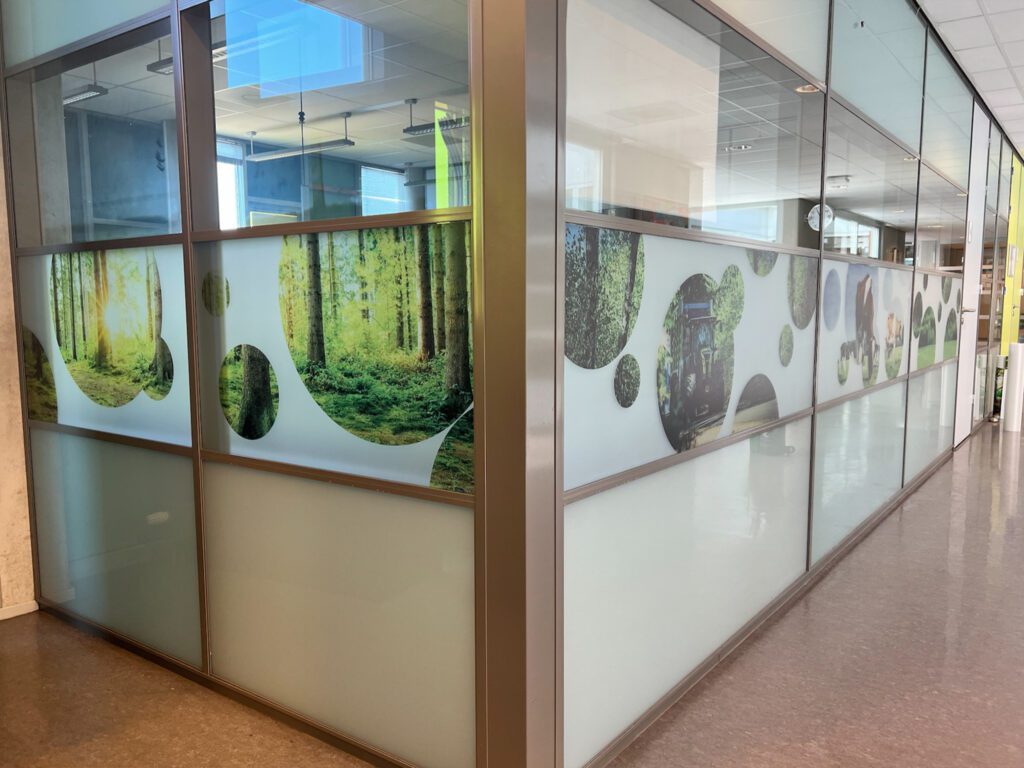 Interieur signing voor Zone.college Doetinchem met grote raamdecoratie in bos- en natuurthema.
