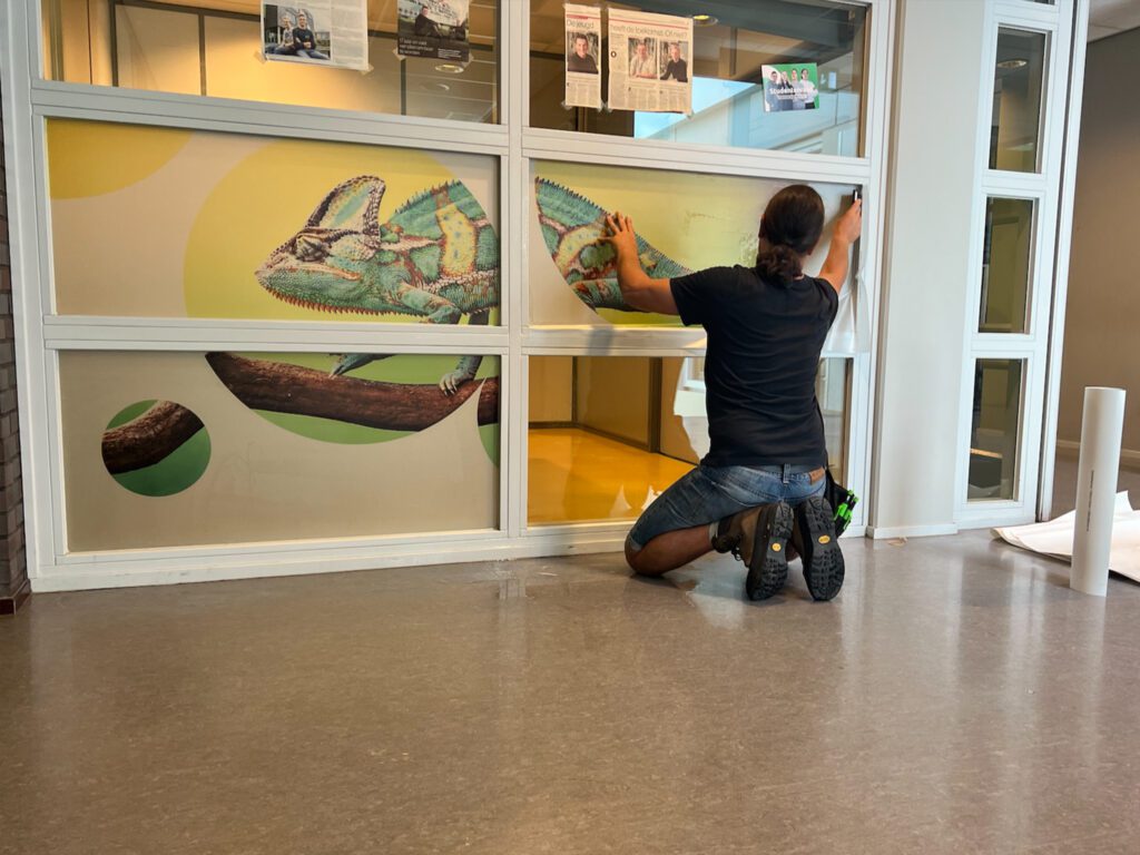 Montage van raamfolie met illustraties voor de visuele inrichting en interieur signing van lokalen bij Zone.college Doetinchem.
