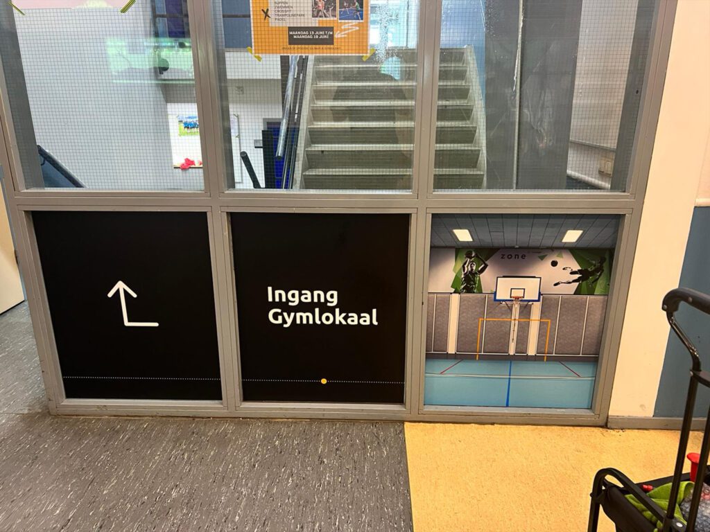 Gymlokaal signing bij Zone.college met duidelijke bewegwijzering op raamfolie.