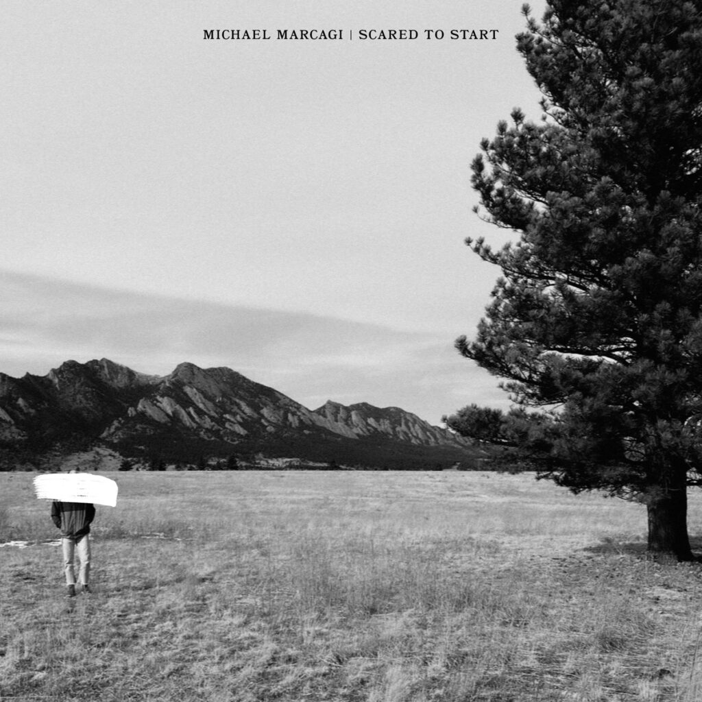 Albumcover van het liedje Scared To Start van Michael Marcagi. Zwart-wit afbeelding van een landschap met grasveld, bergen en bomen.